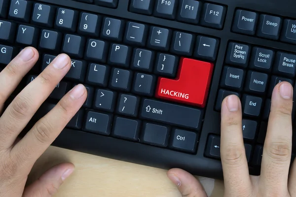 Mãos no teclado do computador com a palavra "Hacking" no botão enter . — Fotografia de Stock