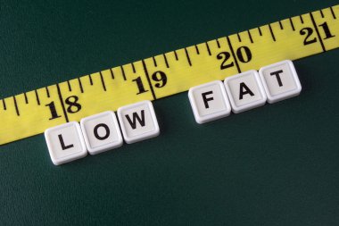 Arrangement of alphabet blocks of words LOW FAT with yellow tape measure