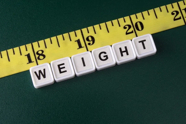 Arrangement of alphabet blocks of word WEIGHT with yellow tape measure — Stockfoto