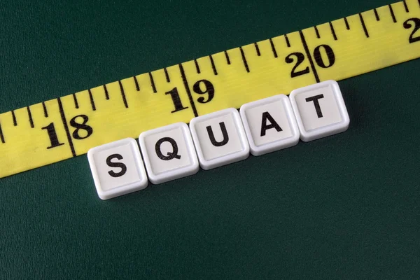 Arrangement of alphabet blocks of word SQUAT with yellow tape measure — ストック写真