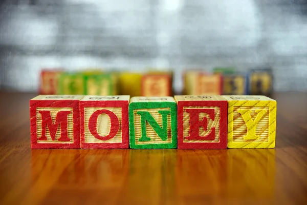 钱单词拼写与多彩木制字母块。选择性的焦点，浅景深. — 图库照片