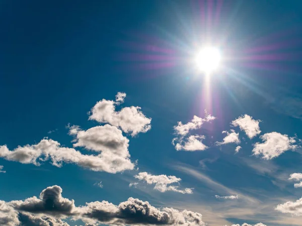 The sun on a background of blue sky with cumulus clouds. Sun rays. White clouds. Blue set. Weather. Synoptic weather forecast. Stratosphere. Space. Background image. Place for text.
