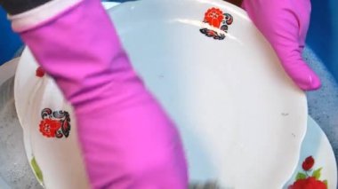 Mutfak tabağını plastik bir kasede elle yıkamak..