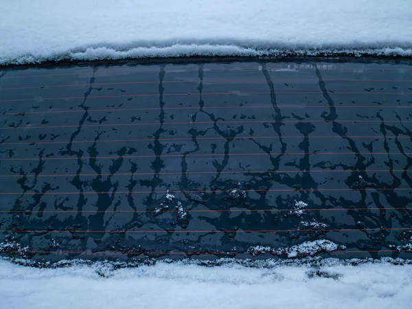Melting snow on the car window glass.