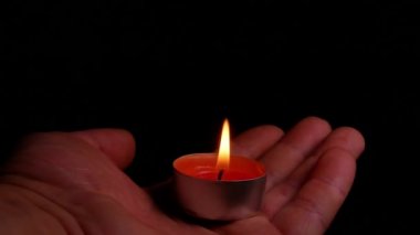 Siyah arka planda yanan bir mum. Karanlıkta yanan bir mumun alevi. İnsan eli. Anma Günü. Anma Günü. Üzüntü. Cenaze hizmetleri. Ateş açın. Video.