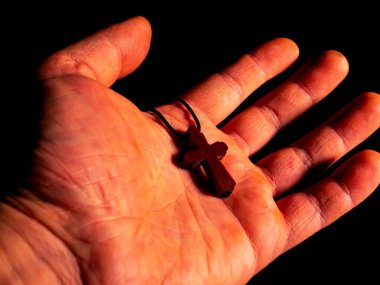 Bir erkeğin avucunda Hıristiyan göğüs kemiği haçı. Hıristiyan göğüs kafesi. Ortodoks dini. Bir adamın eli. Tanrı 'ya inan. Tanrı 'ya dua et. Dindar insanlar. Kilise tılsımı. Kişisel tılsım. Kutsal işaret..