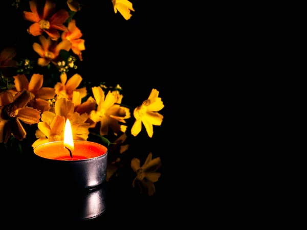 Feuerflamme brennender Wachskerzen auf einem Hintergrund aus Blumen. — Stockfoto