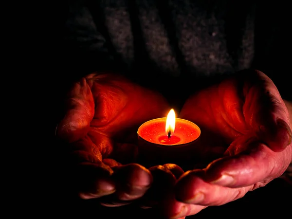 Feuerflamme brennender Wachskerzen in den Handflächen. — Stockfoto