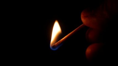 Karanlıkta kibrit kutusuna karşı kibrit yakmak. Yanan kibrit. Kibrit kutusu elinde. Ateş alevi. Ateşleme kıvılcımı. Ateş yak. İnsan eli. Siyah arka plan. Sülfür çok yanıcıdır..