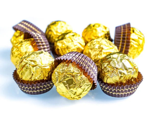 Chocolates redondos en una envoltura de lámina dorada sobre un fondo blanco. — Foto de Stock