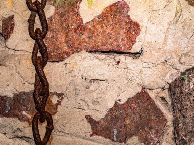 Granit bir duvarın arka planında eski paslı demir zincir.