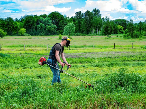 芝刈り機で一人の男が緑の草を切っている 草のトリマー 草を刈れ 芝生の芝刈り機を使用して草を刈る 園芸機器 園芸用具 産業機器 — ストック写真