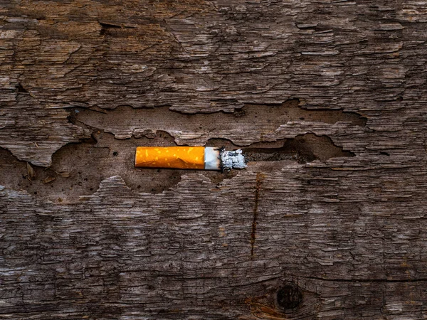 Cigarette butt on a rotten wooden surface. — Foto Stock