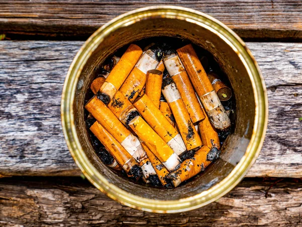 Posacenere da una lattina con mozziconi di sigaretta su un tavolo di legno. — Foto Stock