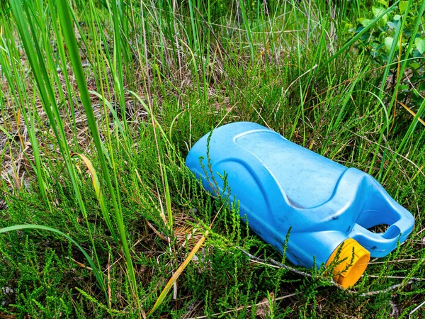 Un bote de plástico azul en un depósito de chatarra en la hierba verde. — Foto de Stock
