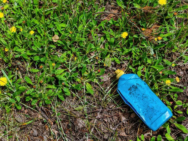 Un bote de plástico azul en un depósito de chatarra en la hierba verde. — Foto de Stock