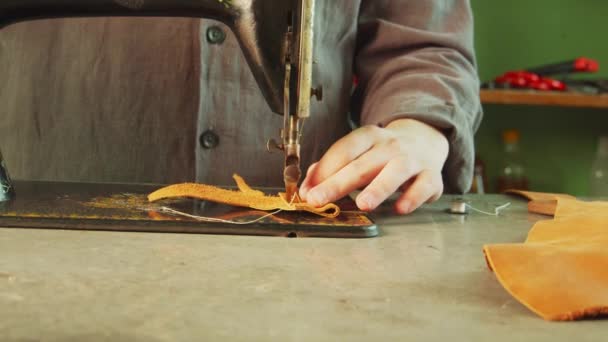 En skräddare i verkstaden gör en exklusiv väska av äkta läder med hjälp av en symaskin. Långsamma rörelser — Stockvideo