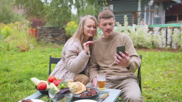 Una giovane coppia in un villaggio isolato fa una videochiamata ai genitori su uno smartphone, rallentamento — Video Stock