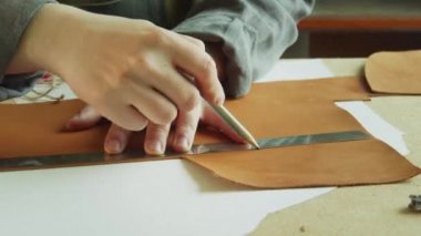 Bir ayakkabıcı onu kesmek için büyük bir parça hakiki derinin üzerine bir kalem ile bir çizgi çizer. Özel ayakkabılar yaratma süreci.