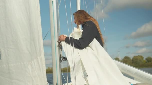 Una hermosa joven deportista estudia el aparejo y aparejo de un yate deportivo. Aprender a levantar una vela. — Vídeos de Stock