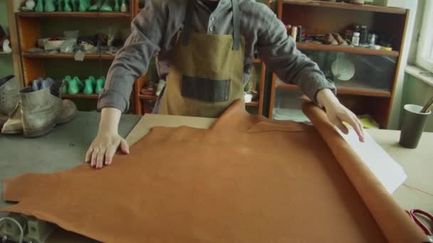 慢动作射击。裁缝为他的初创企业购买了一大卷真皮，用于生产独家作者的皮革配件. — 图库视频影像