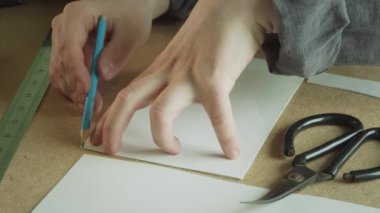 El yapımı giysi üretimi için desenler oluşturmaya yakın çekim. Kalemle bir el kavisli bir çizgi çizer..