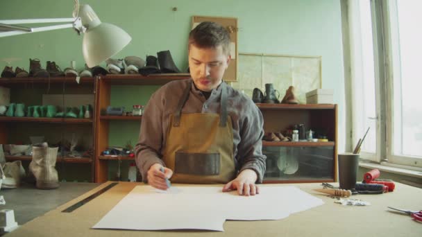 Porträtt av en professionell gammaldags skräddare i verkstaden på jobbet. Förberedelse av ritningar för klädes- och skodesign. — Stockvideo
