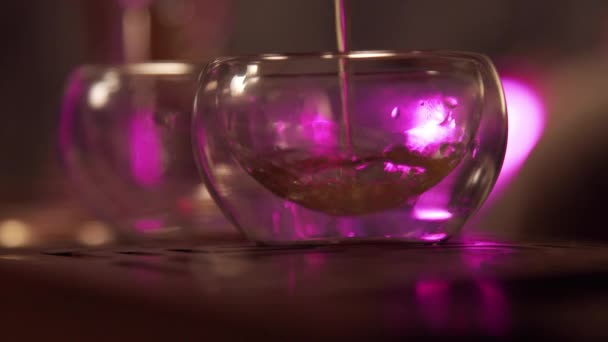 Two glass bowls are filled with a stream of tonic Chinese tea from a teapot at a tea ceremony. Slow motion. — Stock Video