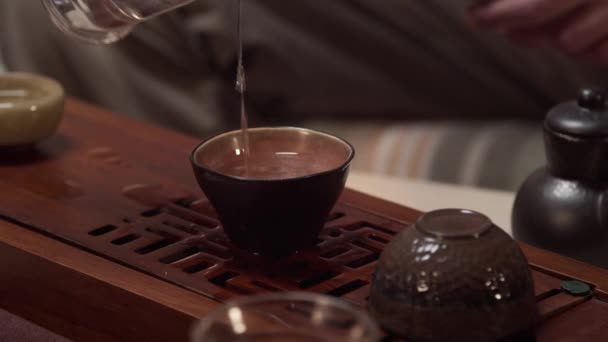 Las manos de un maestro del té chino en el chaban celebran una ceremonia del té en casa. Lava las tazas con agua hirviendo en el chaban. — Vídeos de Stock
