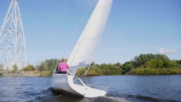 Κατά τη διάρκεια της regatta στο ποτάμι λευκό ιστιοφόρο τρέχει κατά μήκος της ακτής και τα στηρίγματα του τελεφερίκ. Επιβράδυνση. — Αρχείο Βίντεο