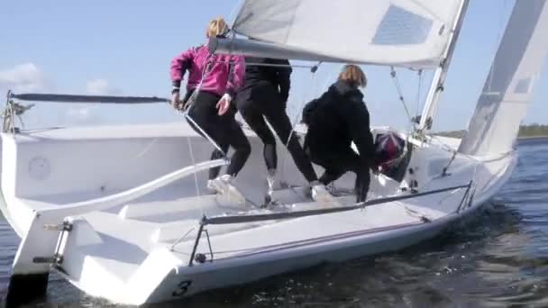 Atletas durante uma regata à vela no lago são transferidos de um lado do barco à vela para o outro para controlar o iate — Vídeo de Stock