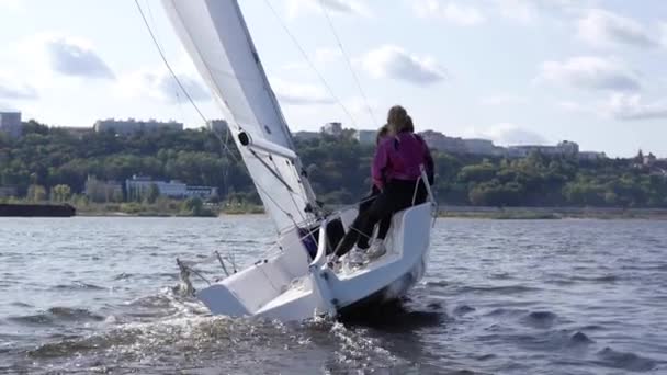 Beautiful view of the city, surrounded by greenery, from the river and a white sailing yacht in slowmotion — Stock Video