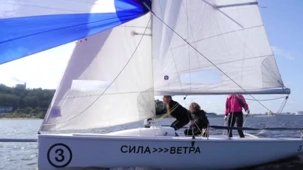 Tre idrottare vika en stor flerfärgad segel under en regatta på floden i slow motion effekt. — Stockvideo