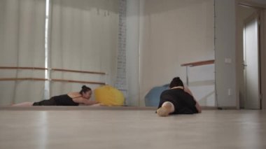 Balerin koridorda bir provada aynanın karşısında oturuyor ve onu geri çekiyor.