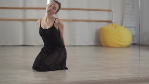 Egy balett iskola próbáján, egy gyönyörű lány táncos kinyújtja a nyakát és a tükör előtt áll. — Stock videók
