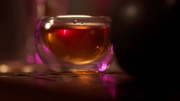 Close-up, hand picks up a cup filled with natural chinese tea from the table. The cozy atmosphere of the tea ceremony with subdued light.