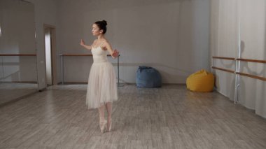 Bale salonundaki tatlı kız bale yapıyor, güzel hareketler ve zıplamalar gösteriyor.