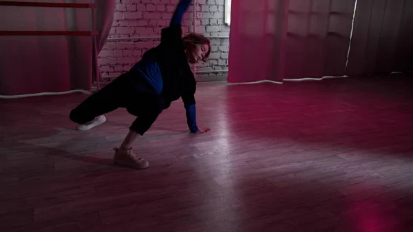 Ένα κορίτσι μελετά την τέχνη του σύγχρονου χορού σε ένα στούντιο σοφίτα με τοίχους από τούβλα και φώτα νέον. — Φωτογραφία Αρχείου