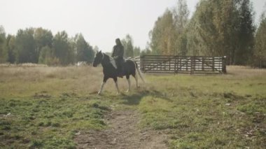 Genç bir binici sabah erkenden yola çıkar engebeli arazide ve ormanda uzun bir ata biner..