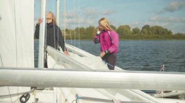 Yelkenli yarışları için hazırlanırken genç sporcular hazırlanıp rıhtımda yelken açacaklar. Yavaş çekim.