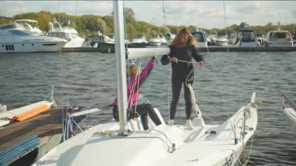 Uma jovem equipe de meninas na vela estuda o armamento da vela do iate. Eles aprendem a definir velas e prender aparelhamento. — Vídeo de Stock