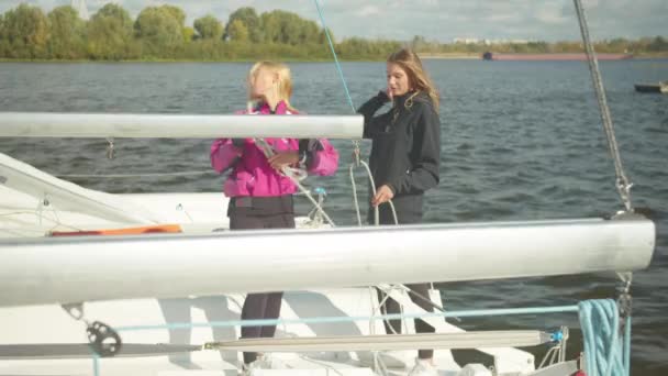 Po skončení sportovní regaty, dívky rozebírají jachty lanoví a připravit na parkování v přístavu. — Stock video