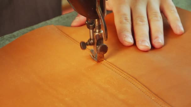 Slow-motion video een naaimachine maakt een steek met een draad op een leren zak. Close-up van de kleermakers hand. — Stockvideo