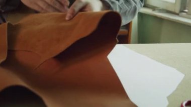 Yüzü olmayan usta bir terzinin elleri. Hakiki deriden yapılmış kadın çantaları yapmak için bir model..