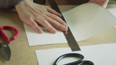 Tecrübeli bir zanaatkarın elleri cetvel boyunca düz bir kağıt katlar. El yapımı ayakkabılar için desenler oluşturuluyor.