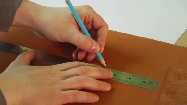 Un cordonnier fait un modèle pour les bottes en cuir véritable. Utilisez un crayon et une règle pour tracer une ligne droite pour la coupe. — Video