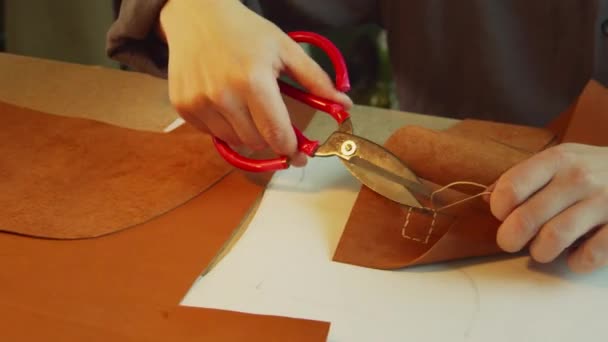 Un abbronzante esperto nel processo di creazione di una borsa da donna. Taglia il filo sartoriale in eccesso e sigilla la punta con un accendino. — Video Stock