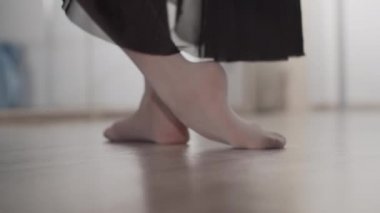 Dans salonundaki ısınma turu sırasında tahta zeminde bir balerin ayaklarının yakın çekimi.