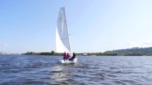 En ung flicka rullar ett extra segel under en segling regatta på en flod nära staden — Stockvideo
