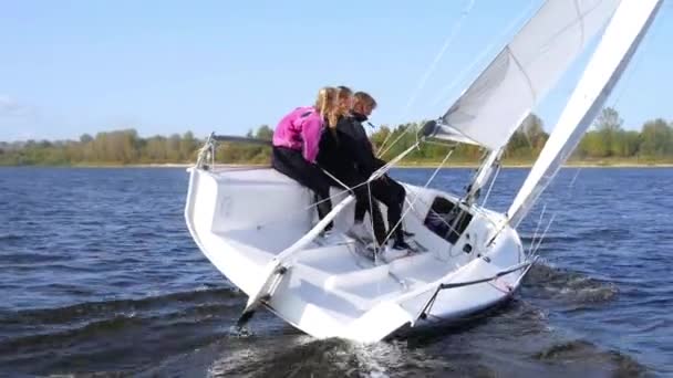 Un homme et deux filles montrent un virage sur un voilier en contrôlant la voile avec leurs pieds et leurs mains — Video